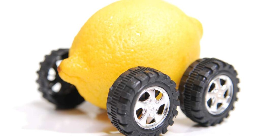 Here's a close-up image of a bright yellow lemon with black wheels. The photo has a white backdrop, making the lemon car stand out.