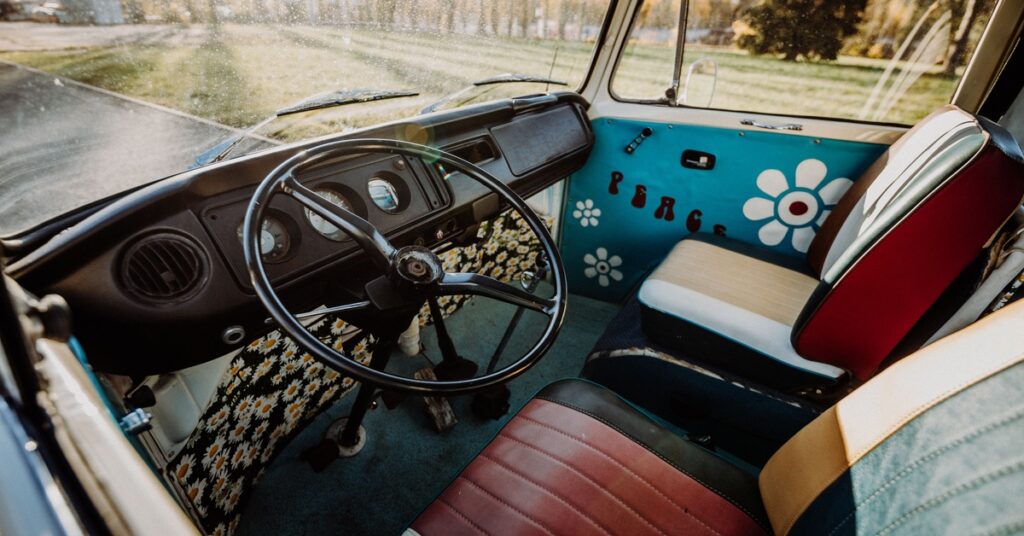 The interior of a Volkswagen Bus with multicolored leather seating and a light-blue design with flowers on the door.