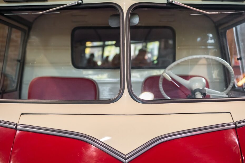 A vintage Volkswagen Bus with beige paint on the top half of the vehicle and red on the bottom half.