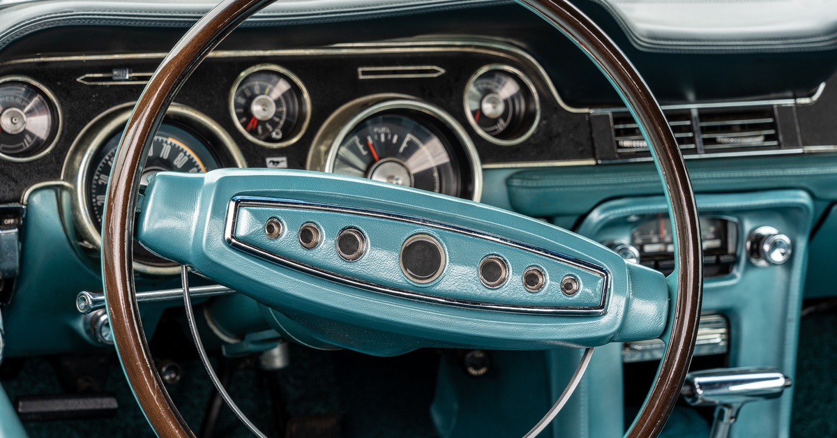 The interior of an old-school car with a blue-and-black design. Installed into the dashboard are raised gauges.