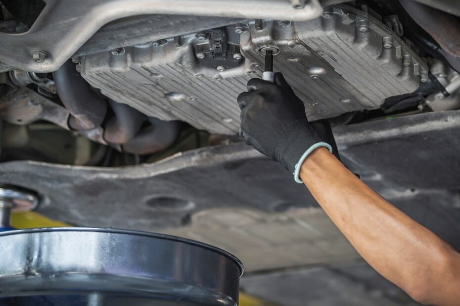The underside of a vehicle's undercarriage. A person's arm reaches up to a cap part of the undercarriage.
