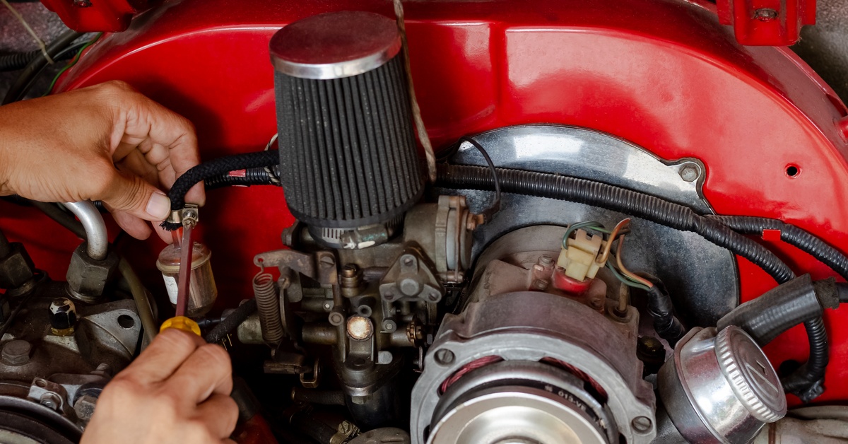 A close-up of the inner components of a car, with a pair of hands holding a screwdriver and working on a connecting part.