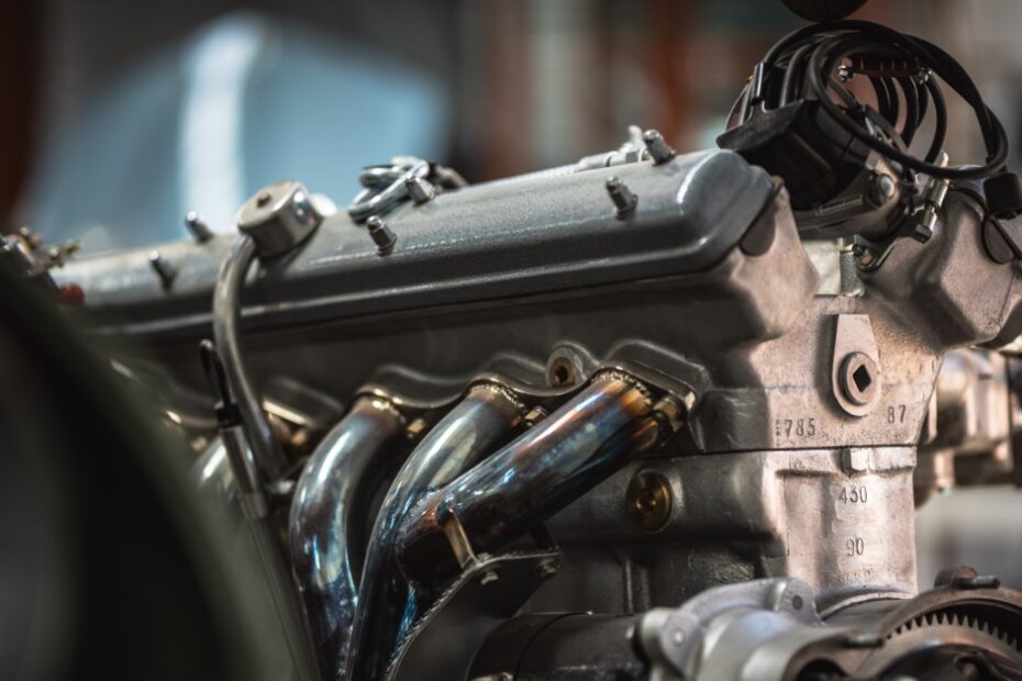 A restored engine for a classic car against a blurry background and car parts in the foreground as well.
