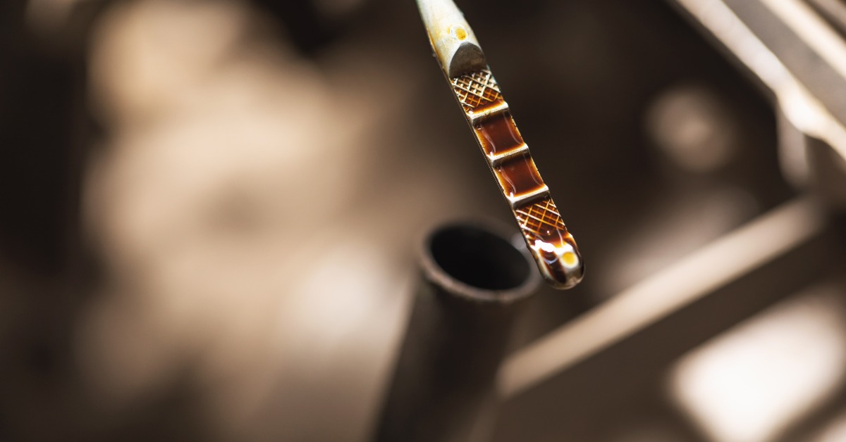 A close-up of the dip stick used to test engine oil levels and quality with a brown oil residue on it.